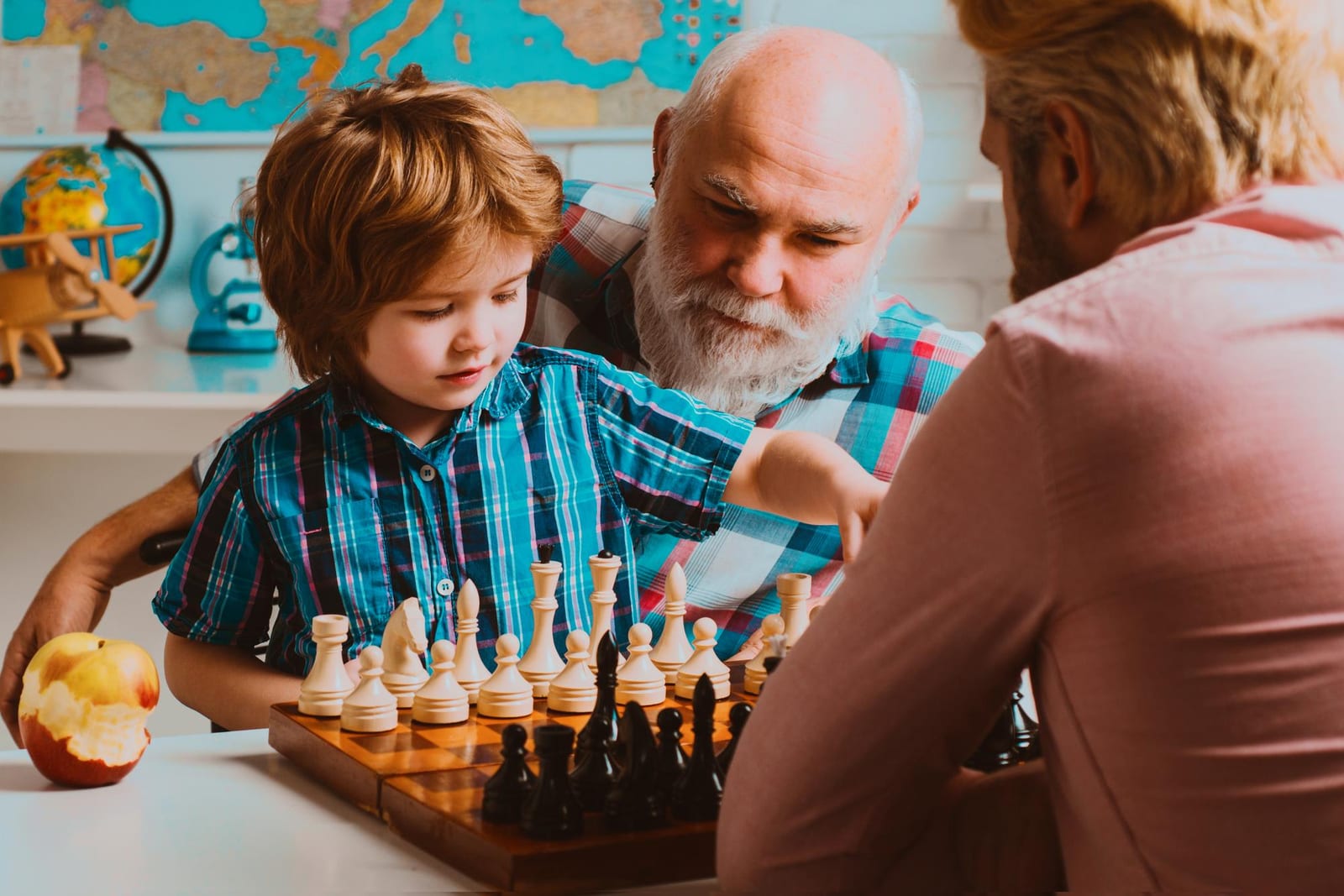 Avô, pai e filho jogando xadrez juntos em família
